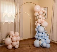 balloons are arranged in the shape of an arch and stand next to a window with drapes