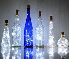 several bottles with lights in them on a reflective surface