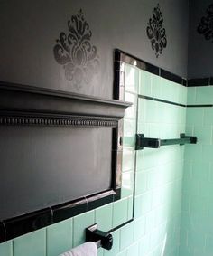 an image of a bathroom setting with green and black tiles on the walls, and white tile in the shower area