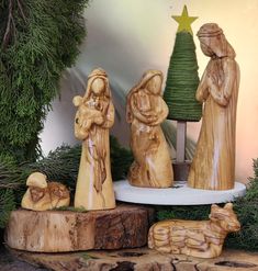 three wooden nativity figurines with a christmas tree in the background