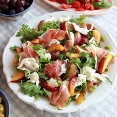 a salad with peaches, prosciutto and blue cheese is on a white plate