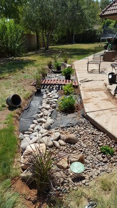 a garden with rocks and gravel in the middle, along side an umbrella covered patio