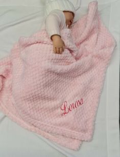 a baby doll is wrapped in a pink blanket with the name lora written on it