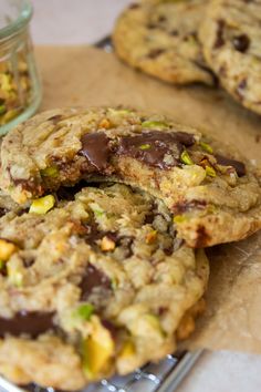 chocolate chip cookies with pistachios and nuts on a cookie sheet next to a jar of dried pistachios