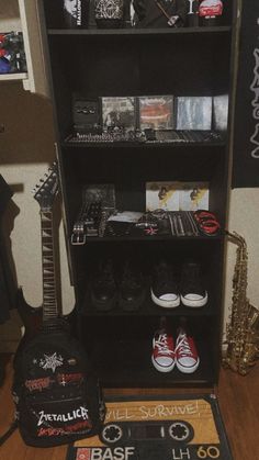 a black book shelf filled with lots of musical instruments and music memorabilia on top of a hard wood floor