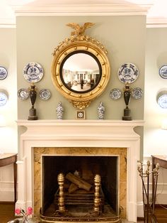 a living room with a fire place and plates on the fireplace mantel above it