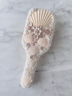 a white hair comb with pearls and flowers on the front, sitting on a marble surface