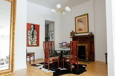 a dining room table with four chairs and a painting on the wall