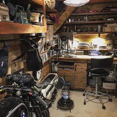 a motorcycle is parked in the garage next to a desk and shelves filled with items