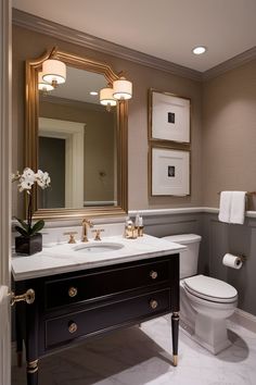 a white toilet sitting next to a sink in a bathroom under a large framed mirror