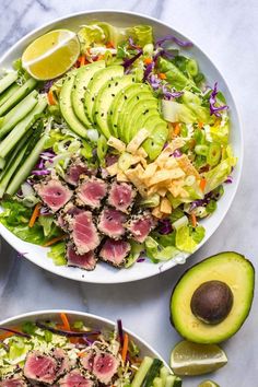 two white bowls filled with tuna, avocado and lettuce next to sliced limes