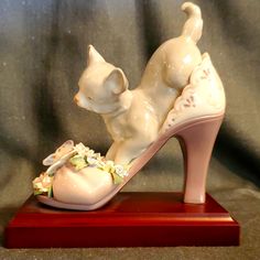 a figurine of a cat sitting on top of a high heeled shoe