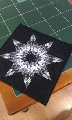 a black and white star quilted onto a wooden table with green tiles on it