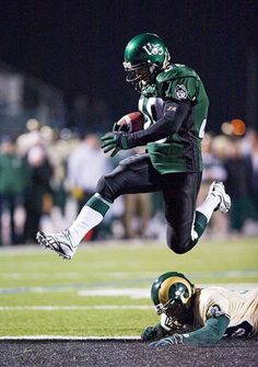 a football player leaps into the air as he is tackled by an opposing team member