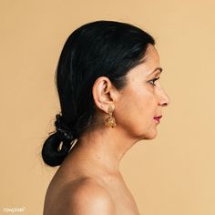 a woman with black hair wearing gold earrings