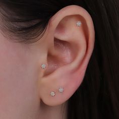 a close up of a person's ear with three small diamond studs