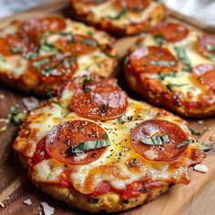 small pizzas with pepperoni and cheese are on a cutting board next to sliced bread