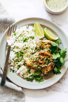 a white plate topped with chicken and rice next to a bowl of cilantro