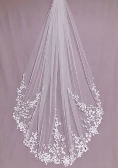 a veil with flowers on it hanging from the ceiling in front of a purple background