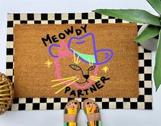 a door mat with a cat face and the words meowdy partner on it