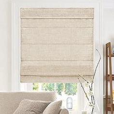 a living room filled with furniture and a window covered in roman blind shades on the windowsill