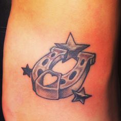 a tattoo on the side of a woman's leg that has a horseshoe and stars around it