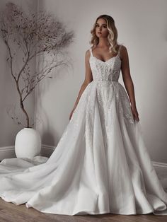 a woman in a white wedding dress standing next to a vase with flowers on it