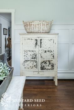 an old white cabinet with a basket on top