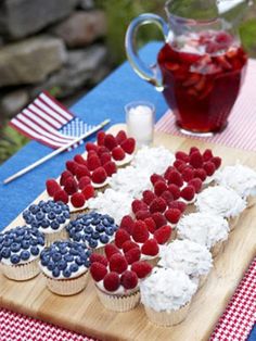 an american flag made out of cupcakes and strawberries on a wooden cutting board