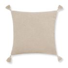 a white pillow with tassels on the edges and a light beige cushion behind it