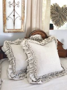 two white pillows with ruffled edges on a bed in front of a framed mirror