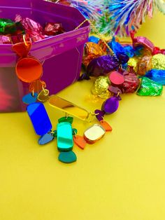 colorful candies are scattered around a plastic container