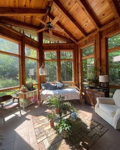 a sun room with lots of windows and plants in the corner, along with a bed