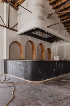 an empty room with exposed pipes and arches on the ceiling, in front of a white wall