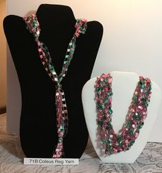 two necklaces are on display next to a mannequin