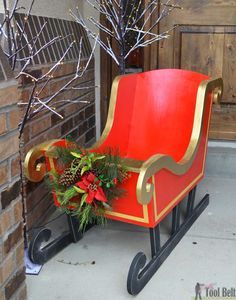 a red and gold sleigh sitting on top of a sidewalk next to a brick building