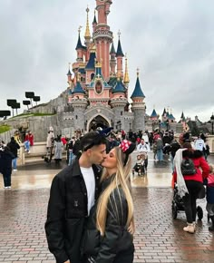 a man and woman kissing in front of a castle with lots of people around it