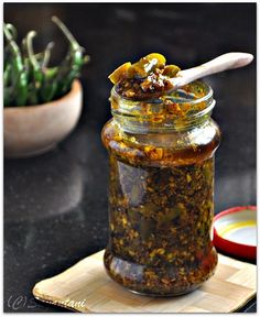 a jar filled with lemon chili pickle on top of a cutting board