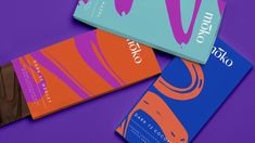 three different colored chocolate bars sitting next to each other on a purple and blue background