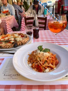 two plates of food on a table with glasses of wine and people sitting at tables in the background