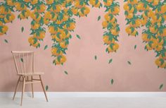 a chair sitting in front of a wall with oranges painted on it and a pink background