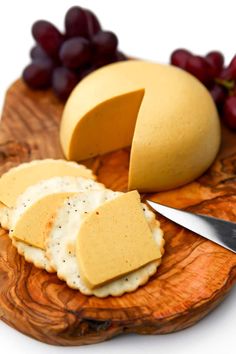 cheese and crackers on a wooden plate with grapes