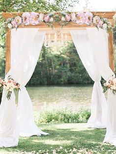 the wedding arch is decorated with flowers and white draping for an outdoor ceremony