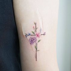 a woman's arm with a cross and flowers on it