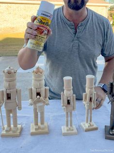 a man standing next to some wooden toy soldiers and holding a can of paint in his hand