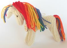 a knitted toy horse with multicolored manes on it's head