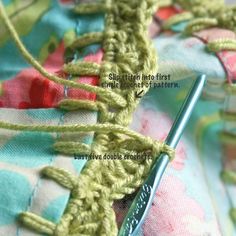 a close up view of a crocheted piece of fabric with a sewing needle