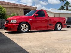 a red pick up truck parked in a driveway