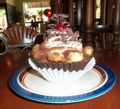 a chocolate cupcake with white frosting and cherries on top sitting on a plate