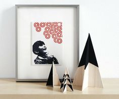 three black and white wooden trees on a table next to a framed photograph with an african man in the background